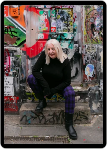 Little Nerd Web Design - Louise Foster - sitting on a stone step in front of a graffiti covered door